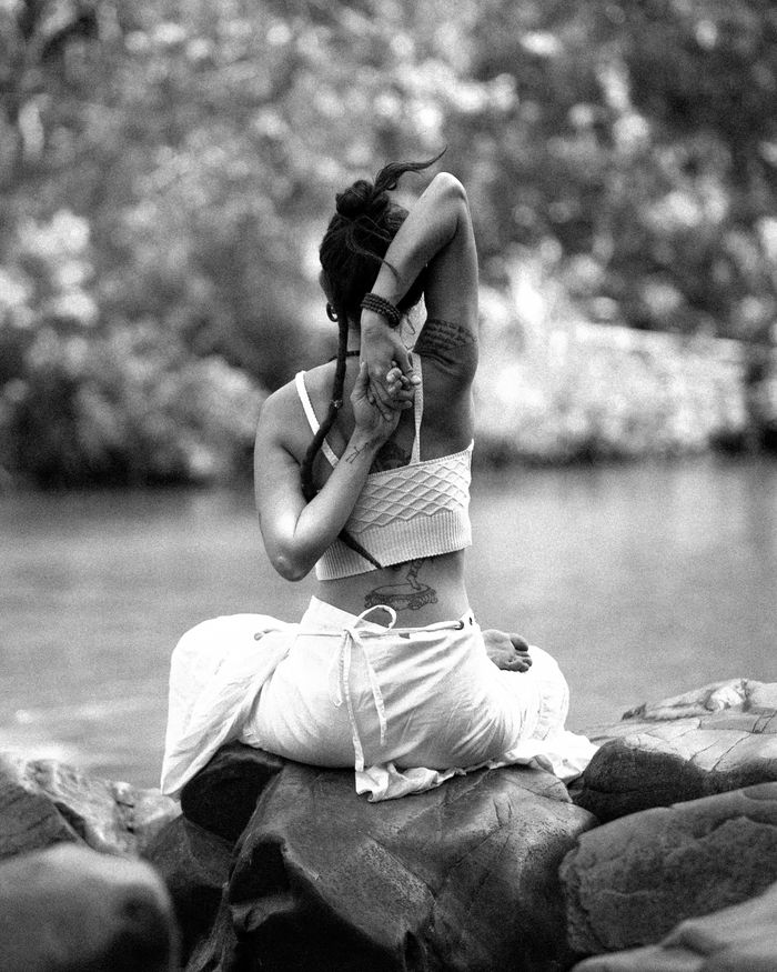 service-01 A woman practicing yoga near a river in a serene outdoor setting, embodying tranquility and focus.